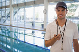 Swimming coach standing by the pool smiling at camera