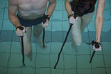 Man and woman holding walking poles in the pool