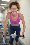 Pretty fit woman on the spin bike smiling at camera