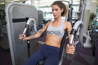 Fit woman using the weights machine for her arms