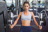 Fit woman using the weights machine for her arms