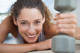 Fit woman smiling at camera holding dumbbell