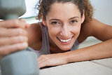 Fit woman smiling at camera holding dumbbell