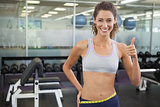 Fit woman measuring her waist and showing thumb up
