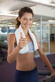 Fit woman wearing towel around shoulders showing thumbs up
