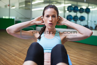 Fit brunette doing sit ups in fitness studio