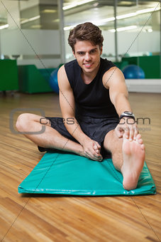 Fit smiling man warming up in fitness studio