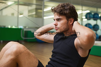 Fit handsome man doing sit ups in fitness studio