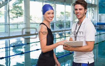 Swimmer smiling at camera with her coach by the pool