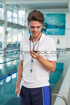 Swimming coach looking at his stopwatch by the pool