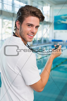 Swimming coach standing by the pool looking at stopwatch