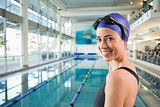 Fit swimmer standing by the pool smiling at camera