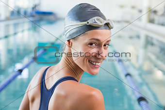 Pretty swimmer by the pool smiling at camera