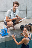 Swimmer with her coach poolside smiling at camera