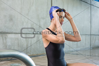 Pretty swimmer sitting at the edge of the swimming pool