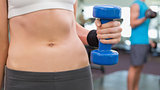 Fit woman holding blue dumbbell mid section