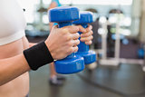 Fit woman exercising with blue dumbbells