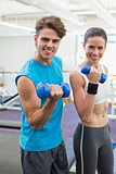 Fit couple exercising together with blue dumbbells