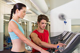 Trainer helping his client set treadmill speed