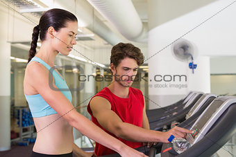 Trainer helping his client set treadmill speed