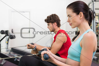 Focused brunette working out on the rowing machine