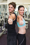 Fit attractive couple giving thumbs up to camera