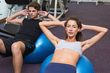 Fit man and woman doing sit ups on exercise ball