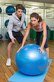 Trainer watching his client using exercise ball