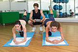Fit women working out together in studio with trainer