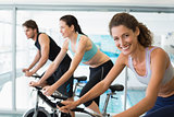 Fit people in a spin class with woman smiling at camera