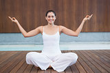 Peaceful happy woman in white sitting in lotus pose