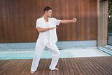Handsome man in white doing tai chi