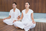Attractive couple in white sitting in lotus pose