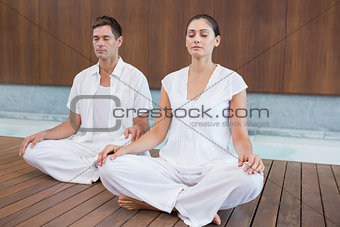 Attractive couple in white sitting in lotus pose