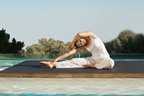 Peaceful brunette in janu sirsasana yoga pose poolside