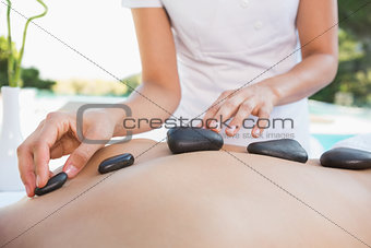 Man getting a hot stone massage poolside