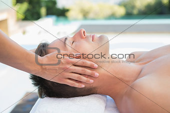 Peaceful man getting a head massage poolside
