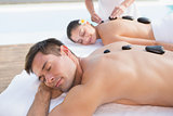 Attractive couple enjoying hot stone massage poolside