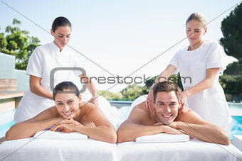Smiling couple enjoying couples massage poolside