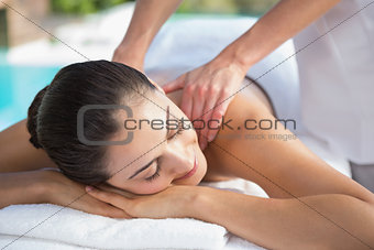 Smiling brunette enjoying a massage poolside