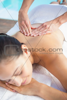 Happy brunette enjoying a massage poolside