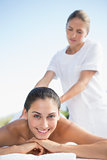 Happy brunette enjoying a massage poolside