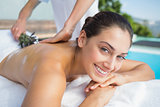 Smiling brunette getting an aromatherapy treatment poolside