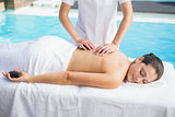 Happy brunette getting a hot stone massage poolside