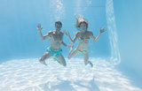 Cute couple smiling at camera underwater in the swimming pool