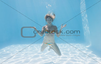 Cute blonde smiling at camera underwater in the swimming pool
