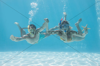 Cute couple underwater in the swimming pool with snorkel and starfish