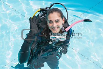 Smiling woman on scuba training in swimming pool making ok sign