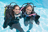 Smiling friends on scuba training in swimming pool making ok sign