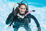 Smiling woman on scuba training in swimming pool showing thumbs up